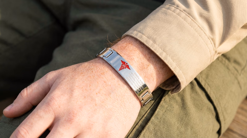 Close-up of a medical alert bracelet on a Scout's wrist, showing the medical symbol and engraved health information